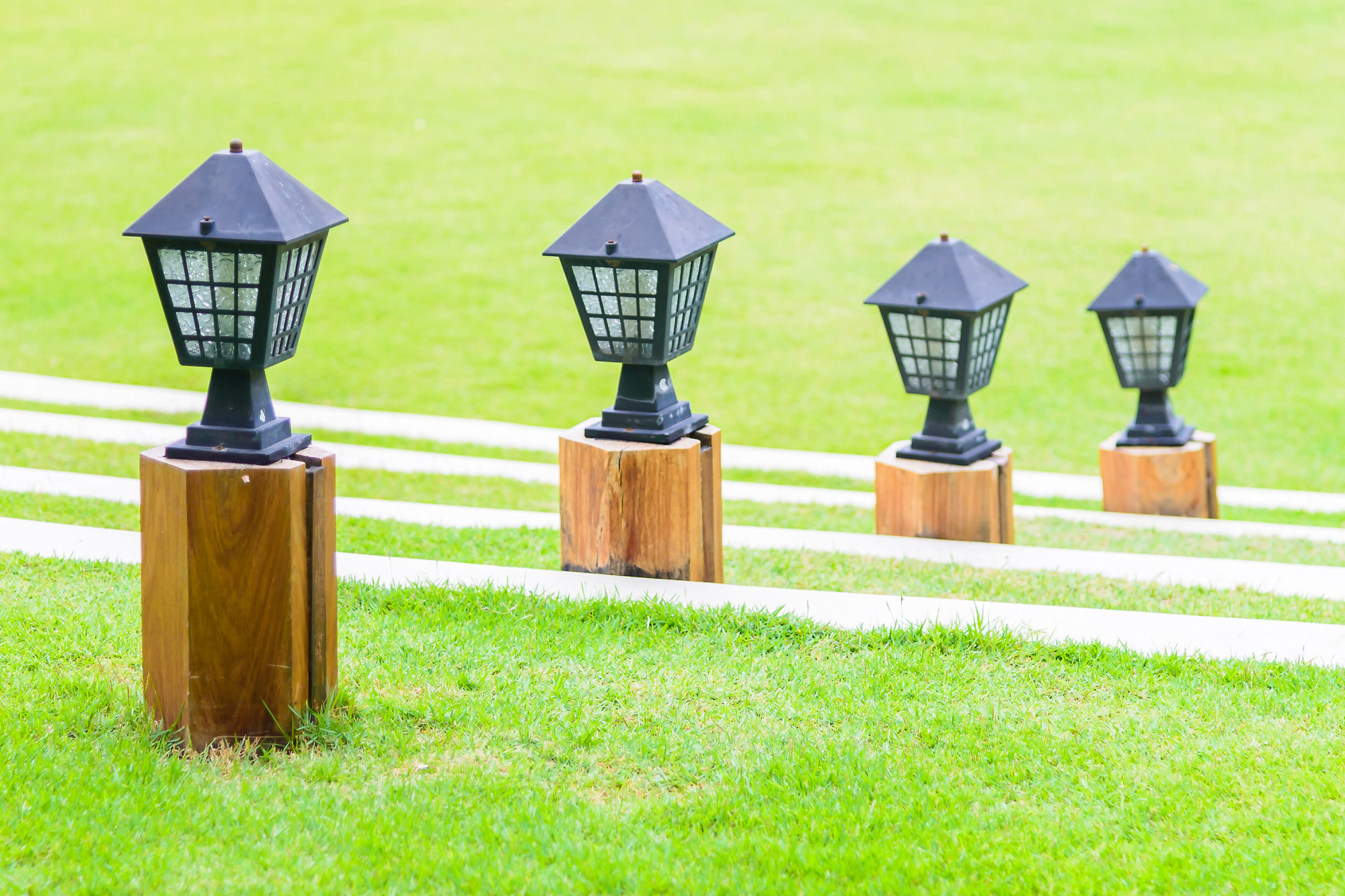 Decorative garden lights line a staircase on a bright green lawn.